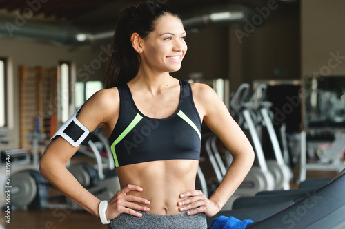 A beautiful young woman (girl) smiles at the camera while she is training at the gym. Concept: Sport, love for sport, fitness.