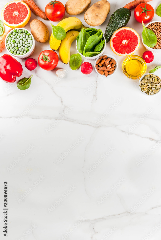 Healthy food background, trendy Alkaline diet products - fruits, vegetables, cereals, nuts. oils, white marble background above copy space vertical
