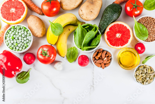 Healthy food background, trendy Alkaline diet products - fruits, vegetables, cereals, nuts. oils, white marble background above copy space