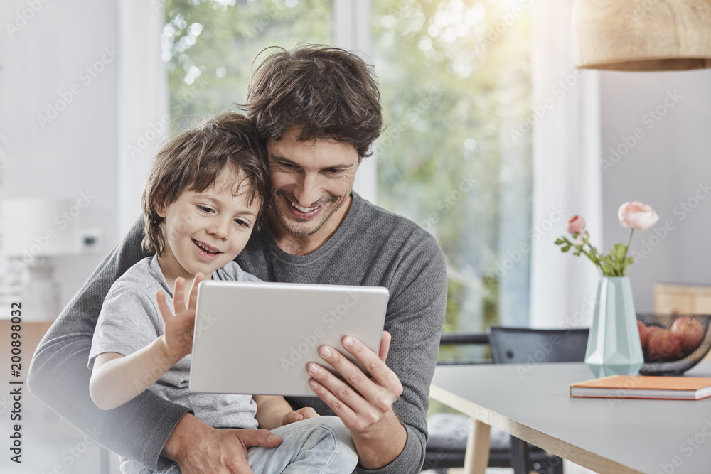 Happy father and son using tablet at home together Happy father and son using tablet at home together