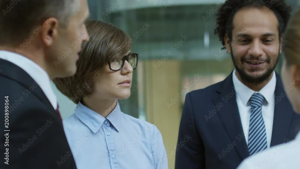 Pretty female business leader in eyeglasses standing with male colleagues and talking about project Pretty female business leader in eyeglasses standing with male colleagues and talking about project