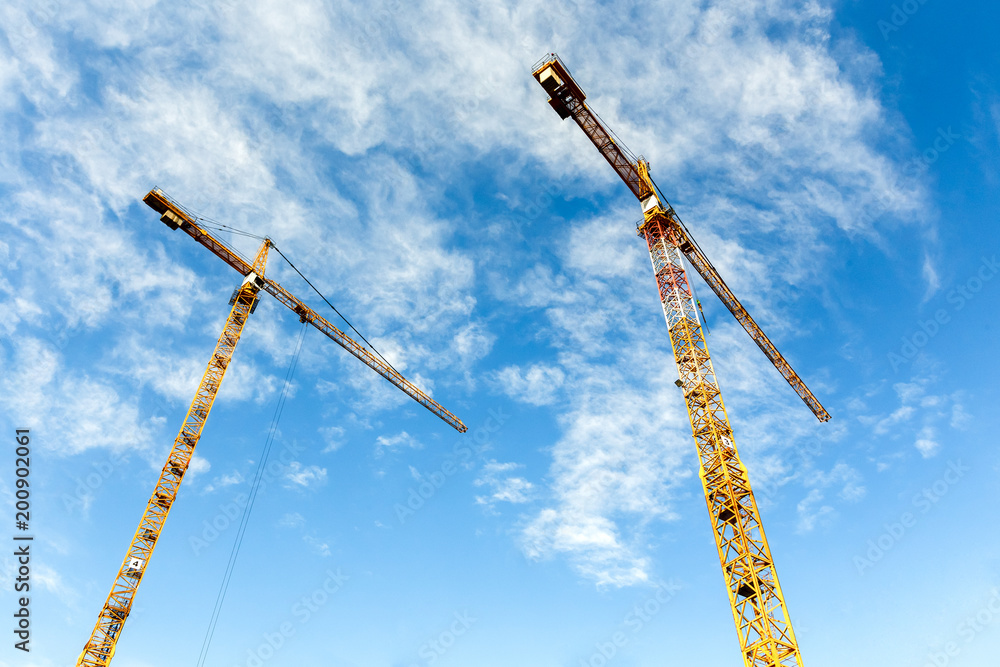 Two high tower cranes work on the construction of new homes Two high tower cranes work on the construction of new homes