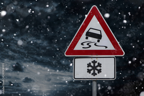 Warnschild für spiegelglatte Strasse durch Schnee und Eis