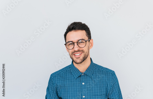 Portrait of handsome smart-looking smiling male posing for social advertisement wearing blue shirt and glasses, isolated on white background with copy space for your promotional information or content
