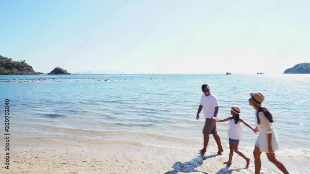 Two happy parents and their daughter enjoying holiday on the beach while walking and holding hands together in Komodo Island near Bali, Indonesia Two happy parents and their daughter enjoying holiday on the beach while walking and holding hands together in Komodo Island near Bali, Indonesia