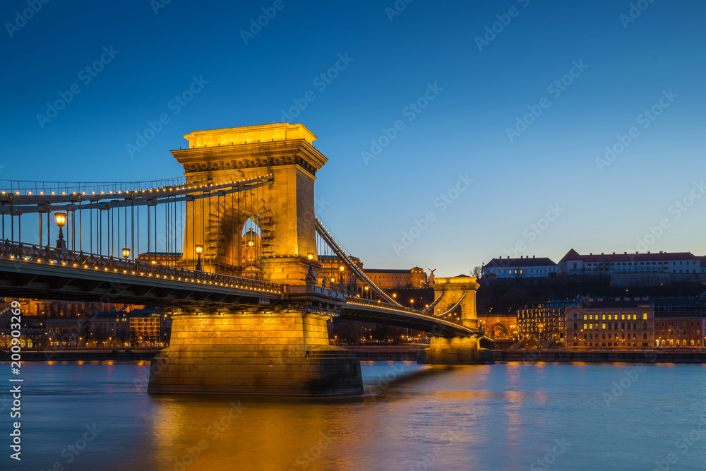 Obraz premium Budapest, Hungary - Illuminated Szechenyi Chain Bridge over River Danube and Buda Castle Royal Palace at blue hour with clear blue sky