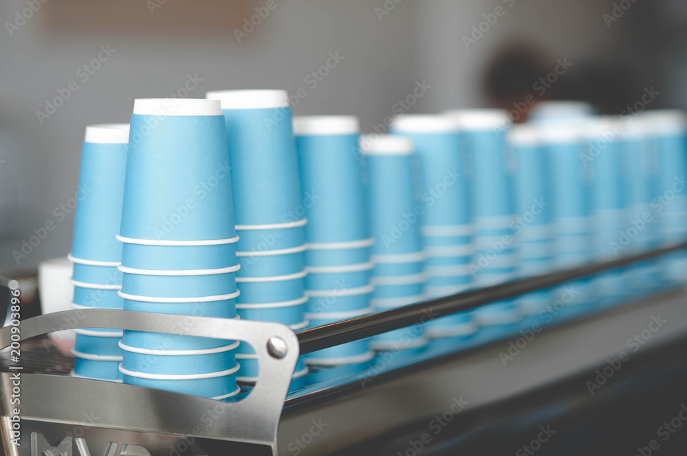 A stack of blue paper cups lies on the rack in a row A stack of blue paper cups lies on the rack in a row