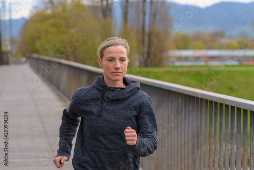 Slender athletic woman jogging on a bridge