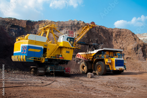 Excavator in the quarry loads the dumper with iron ore.