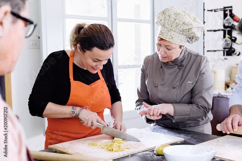 Chef explaining how to make tagliatelle cutting fresh pasta with knife photo