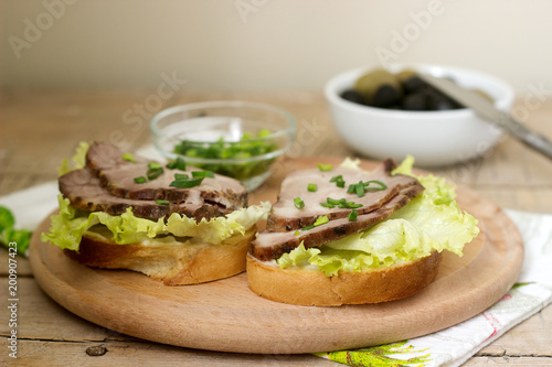 Appetizing sandwiches with meat, lettuce and sauce served with olives. Rustic style. photo