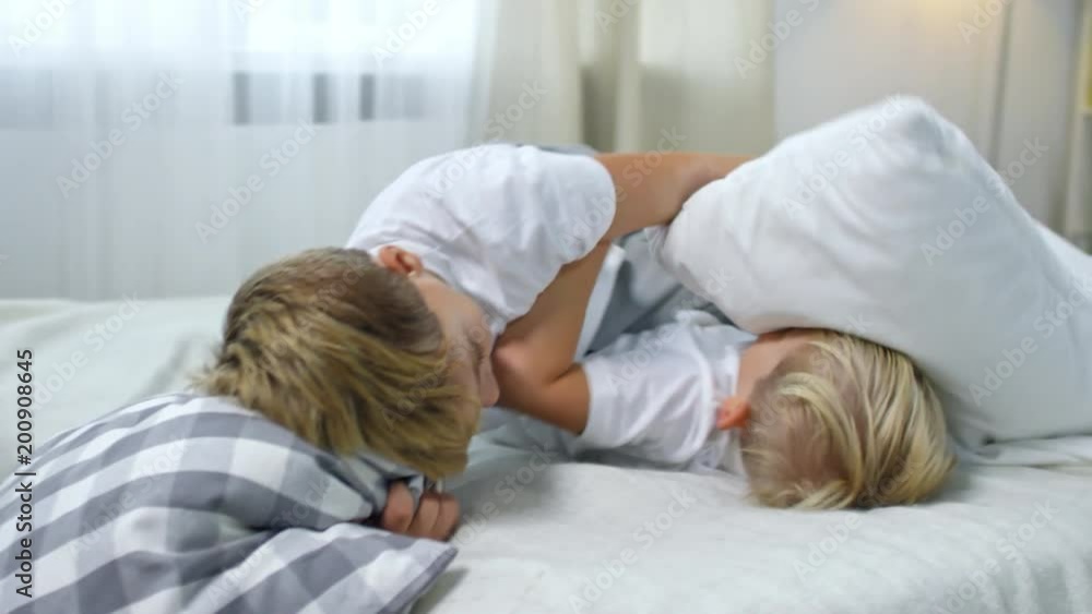 Close up shot of two energetic boys of primary school age going crazy when fighting with pillows on bed Close up shot of two energetic boys of primary school age going crazy when fighting with pillows on bed