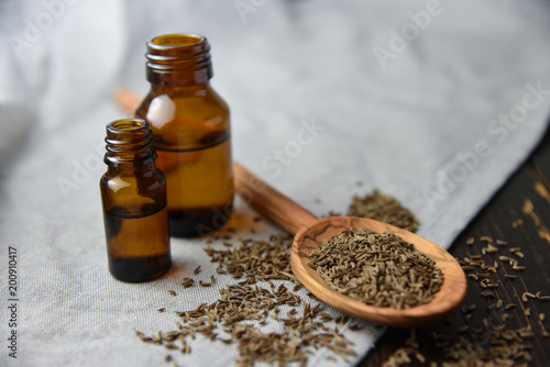 caraway oil and seeds on wooden spoon and essential oil