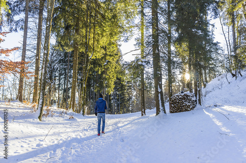  Person walking between snowy trees with sunshine in Fussen