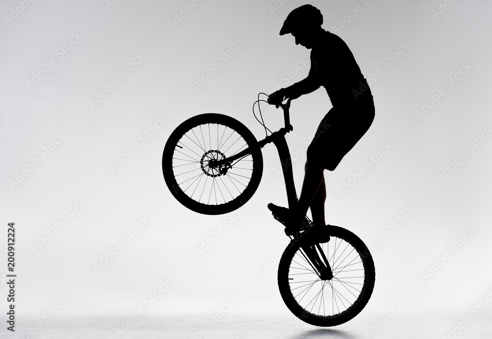 Fototapeta premium silhouette of trial biker performing bunny hop on white