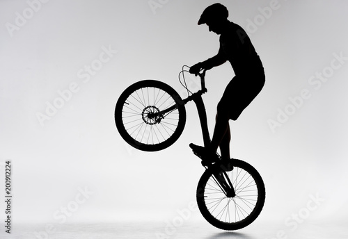 silhouette of trial biker performing bunny hop on white
