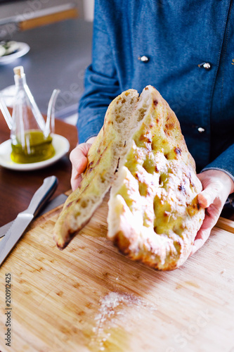 Chef cutting focaccia bread in two halves photo