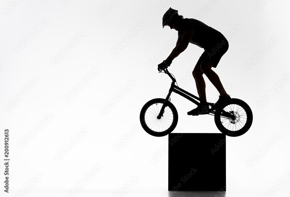 Obraz premium silhouette of trial cyclist balancing on cube on white
