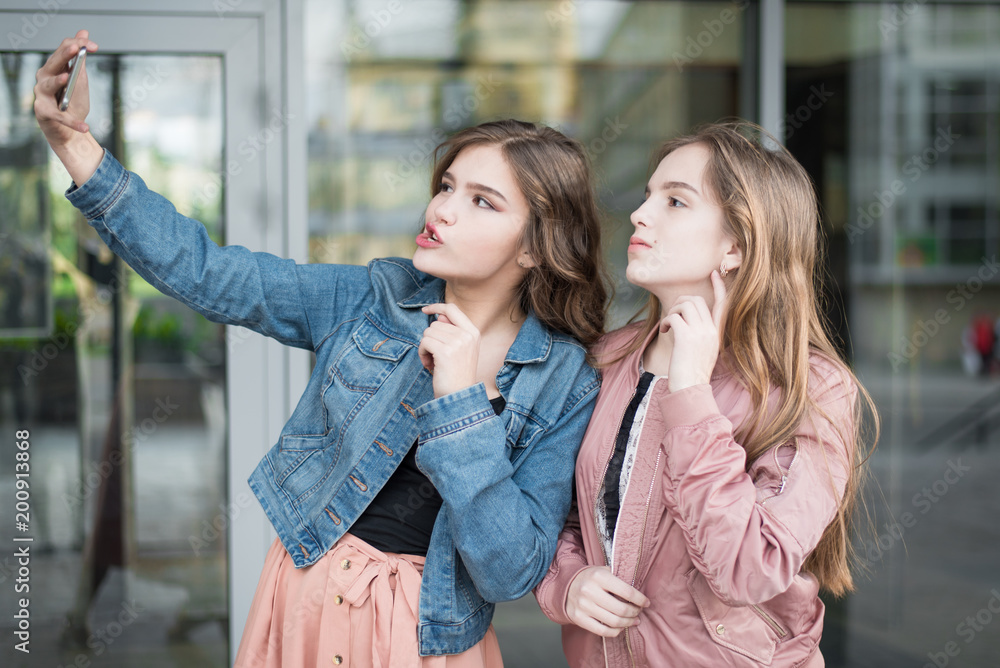 Lifestyle sunny image of best friend girls taking selfie on camera, crazy emotions , happy vacations, shopping day. Cute teenage girls, sisters. holidays and tourism, modern technology concept .