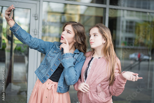 Lifestyle sunny image of best friend girls taking selfie on camera, crazy emotions , happy vacations, shopping day. Cute teenage girls, sisters. holidays and tourism, modern technology concept .