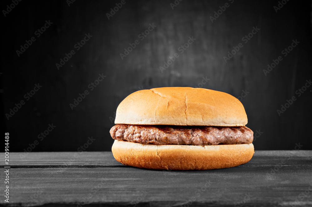Plain beef burger on wooden table isolated on black background Stock Photo
