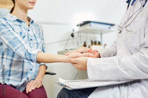 Doctor checking pulse of his female patient at hospital