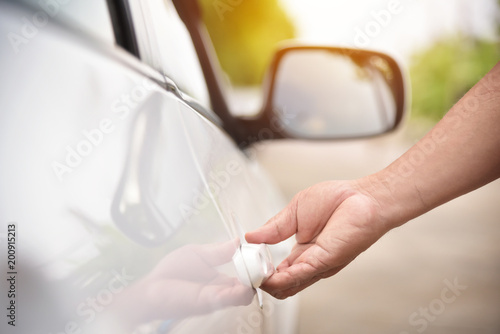 Man hand holding door handle of a car.