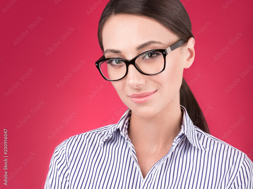Closeup Studio portrait of young attractive woman with glasses on a red background