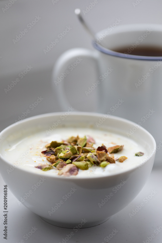 Joghurt mit Pistazien zum Frühstück mit Becher Ceylon Assam Tee Joghurt mit Pistazien zum Frühstück mit Becher Ceylon Assam Tee