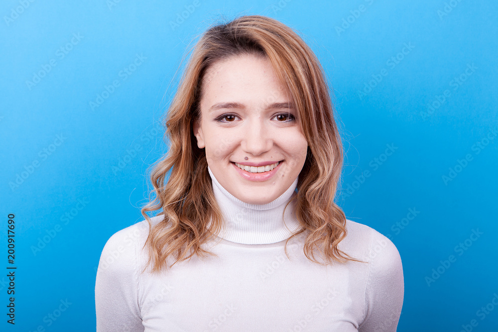 Portrait of gorgeous woman smiling on blue background in studio photo Portrait of gorgeous woman smiling on blue background in studio photo