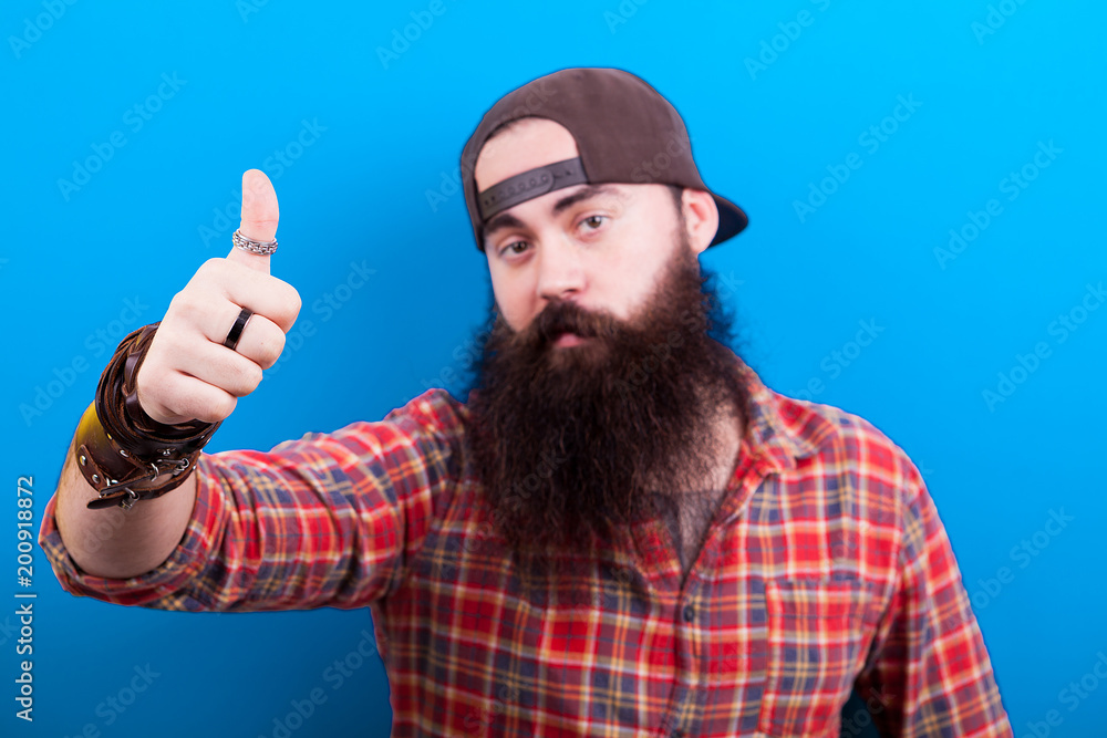 Happy long bearded man showing a thumbs up on blue background Happy long bearded man showing a thumbs up on blue background