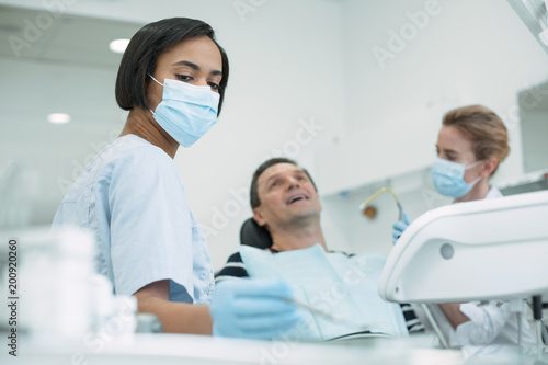 Our usual work. Concentrated skilled dentist wearing a mask and the patient sitting in the chair