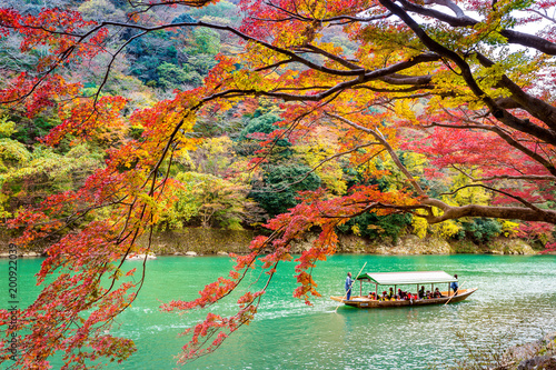 Boatman punting the boat at river. Arashiyama in autumn season along the river in Kyoto, Japan.