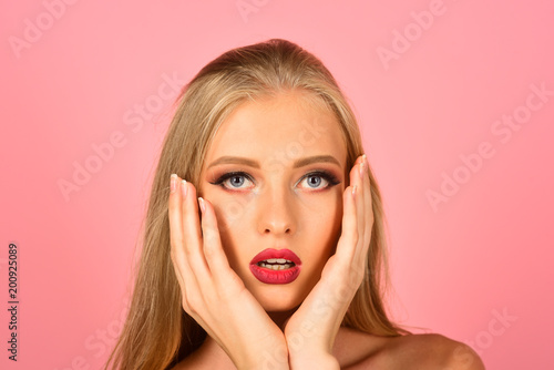 Skincare, healthcare, spa, beauty - woman with clean fresh skin, red lips, touching hands face. Sexy lady makeup for party. Isolated on pink background.