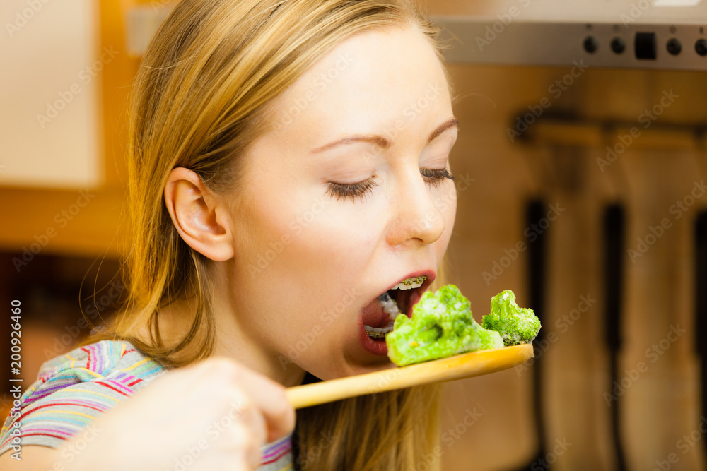 Woman tasting stir fry vegetable from pan