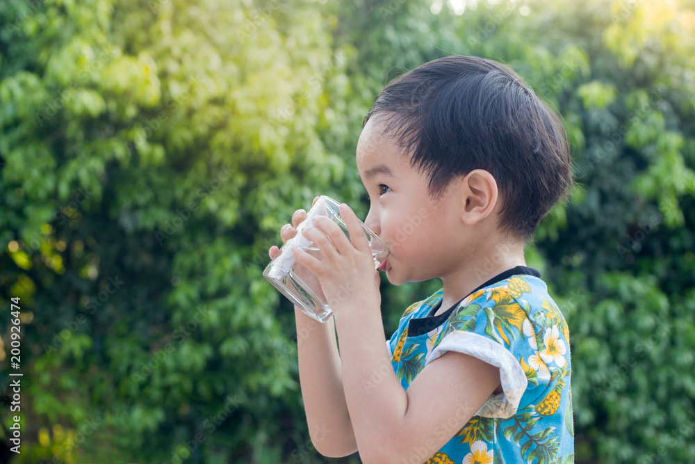 Asian Cute Boy drinking water for Healthy and Refreshing with green tree background. Asian Cute Boy drinking water for Healthy and Refreshing with green tree background.