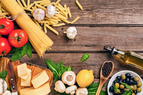Ingredients for spaghetti with basil, tomatoes, cheese on wooden background, top view, place for text