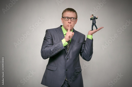 Curious and amazed business man listens attentively other person on his palm hand isolated on gray background. Telling the secrets concept. The lies.