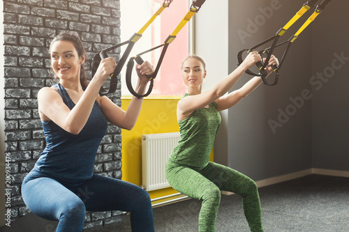 Women performing TRX suspension training in gym photo