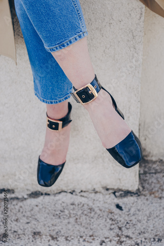 detail shot of a fashion outfit. stylish blogger wearing black ankle strap high heel sandal shoes, and denim vintage jeans. street style.