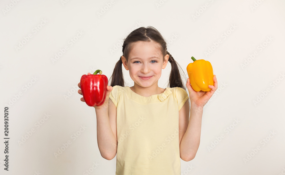 Happy little girl with bell peppers over white background Happy little girl with bell peppers over white background