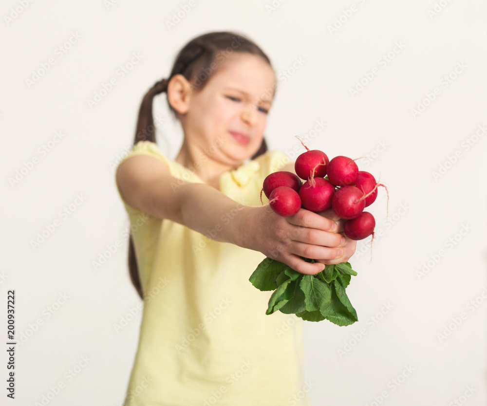 Disgusted little girl with radish over white background Disgusted little girl with radish over white background