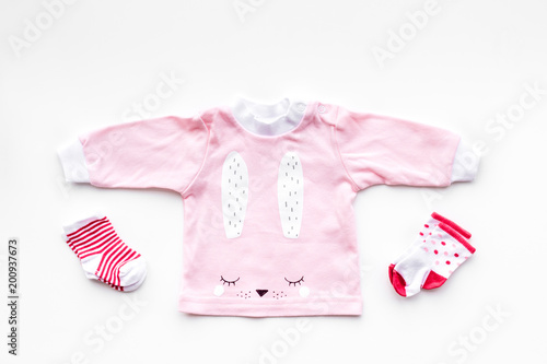 Newborn baby's background. Clothes for small girl with booties on white top view copy space
