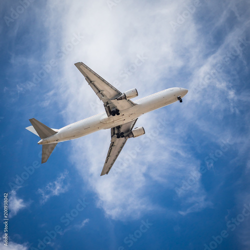 Passenger carrier airplane flying on the blue cloudy sky.