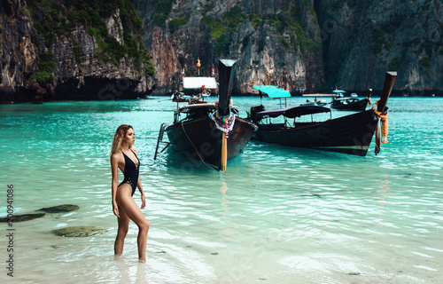 Sexy young beautiful russian girl in little bright bikini. Slim body woman on tropical beach in Thailand. Model vacation photo shoot. Happiness summer sunrise blue sea coral white sand. Tanned skin