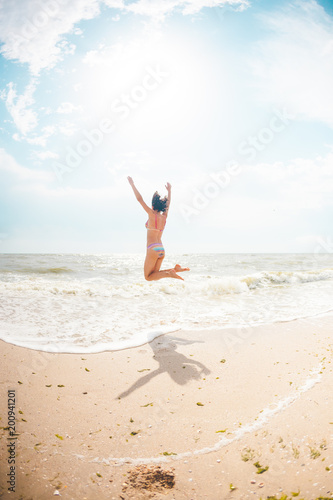 A girl is jumping on the beach.