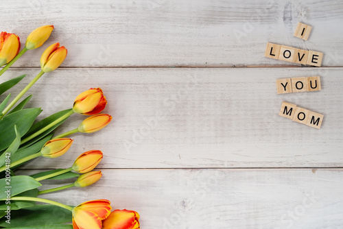 Yellow and red tulips on whitewashed wood with Mother's Day message