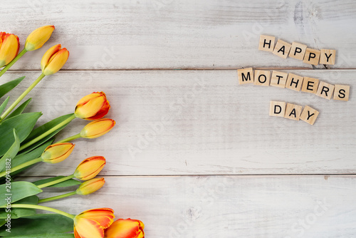 Yellow and red tulips on whitewashed wood with Mother's Day message
