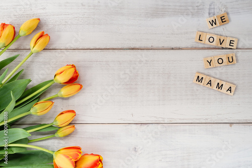 Yellow and red tulips on whitewashed wood with Mother's Day message