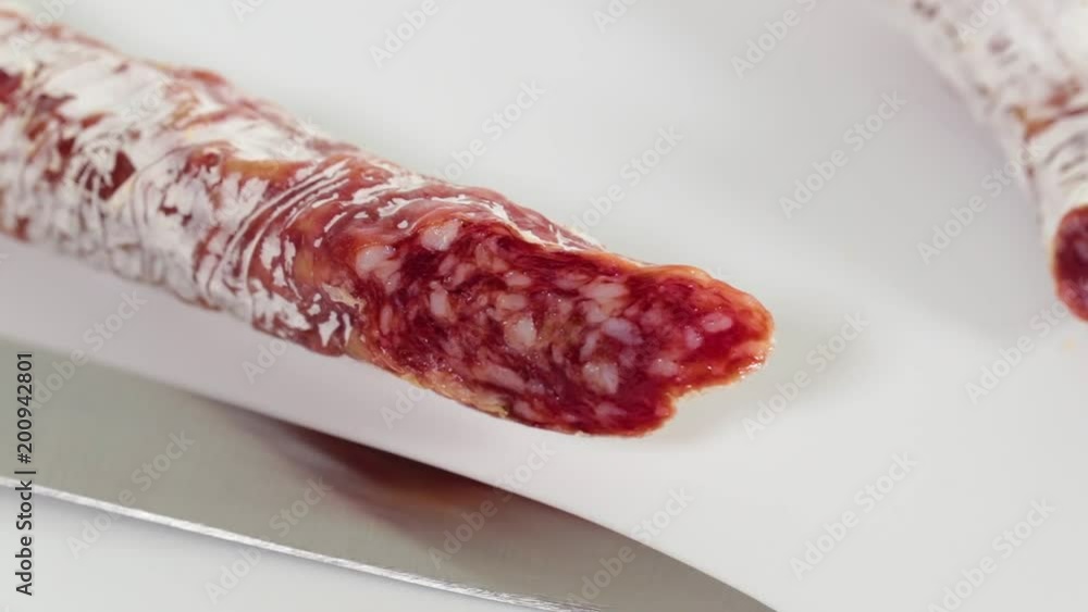 Woman slicing tasty too dry italian sausage on table. She cannot cut it with knife.